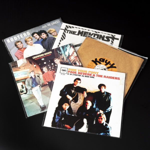 Assorted 45 RPM vinyl records in resealable polypropylene outer sleeves displayed on black surface