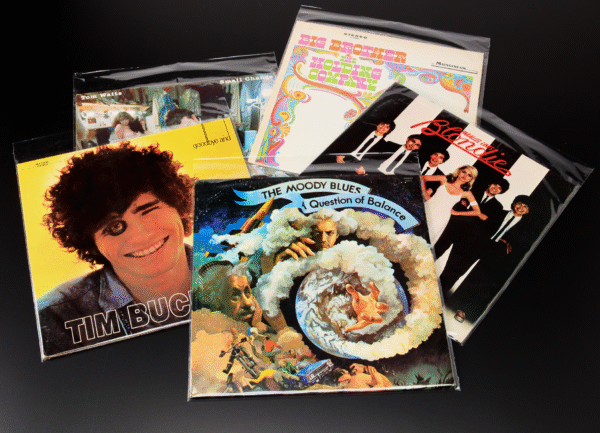 Stack of vinyl records in resealable polypropylene outer sleeves on black background