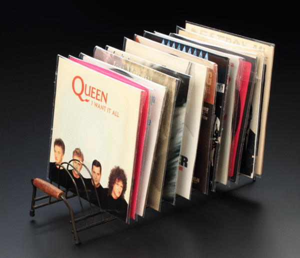 Multiple 7-inch vinyl records in protective resealable sleeves, displayed in a vintage metal record rack